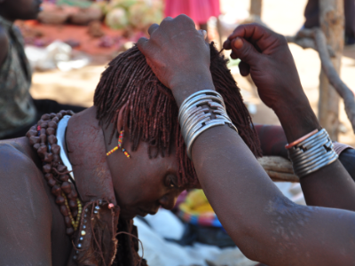 A Hamer woman's hair is braided with red clay